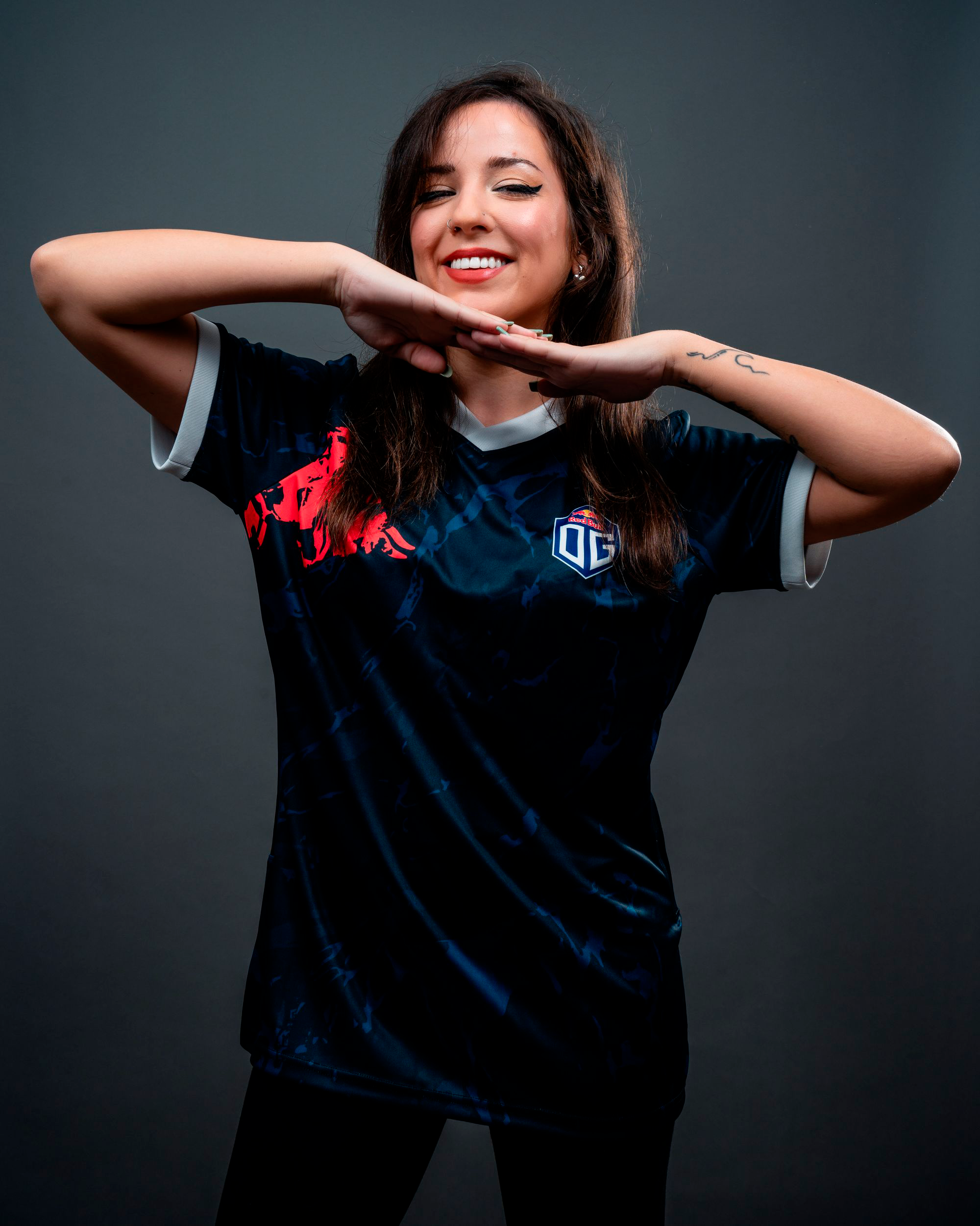 A female model wearing the OG jersey with the OG logo on the left side and a bull logo on the right side, with white highlights around the neck and sleeves.