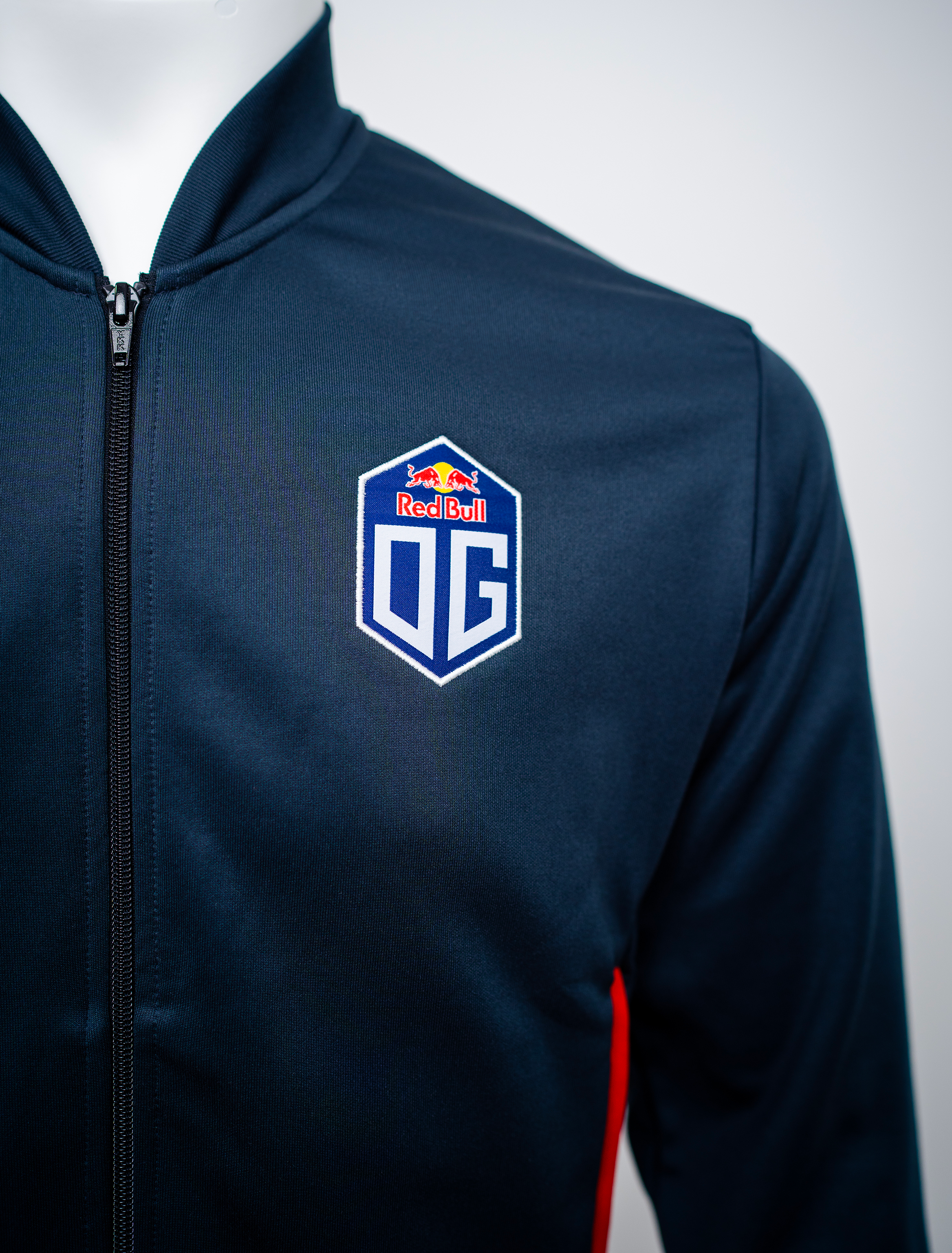 Close-up view of the left side of the pro jacket in dark blue, prominently displaying the OG logo.