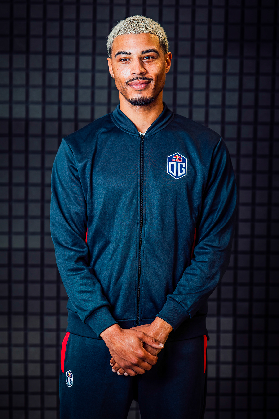 A male model wearing dark blue pro jacket and pants prominently featuring the OG logo.