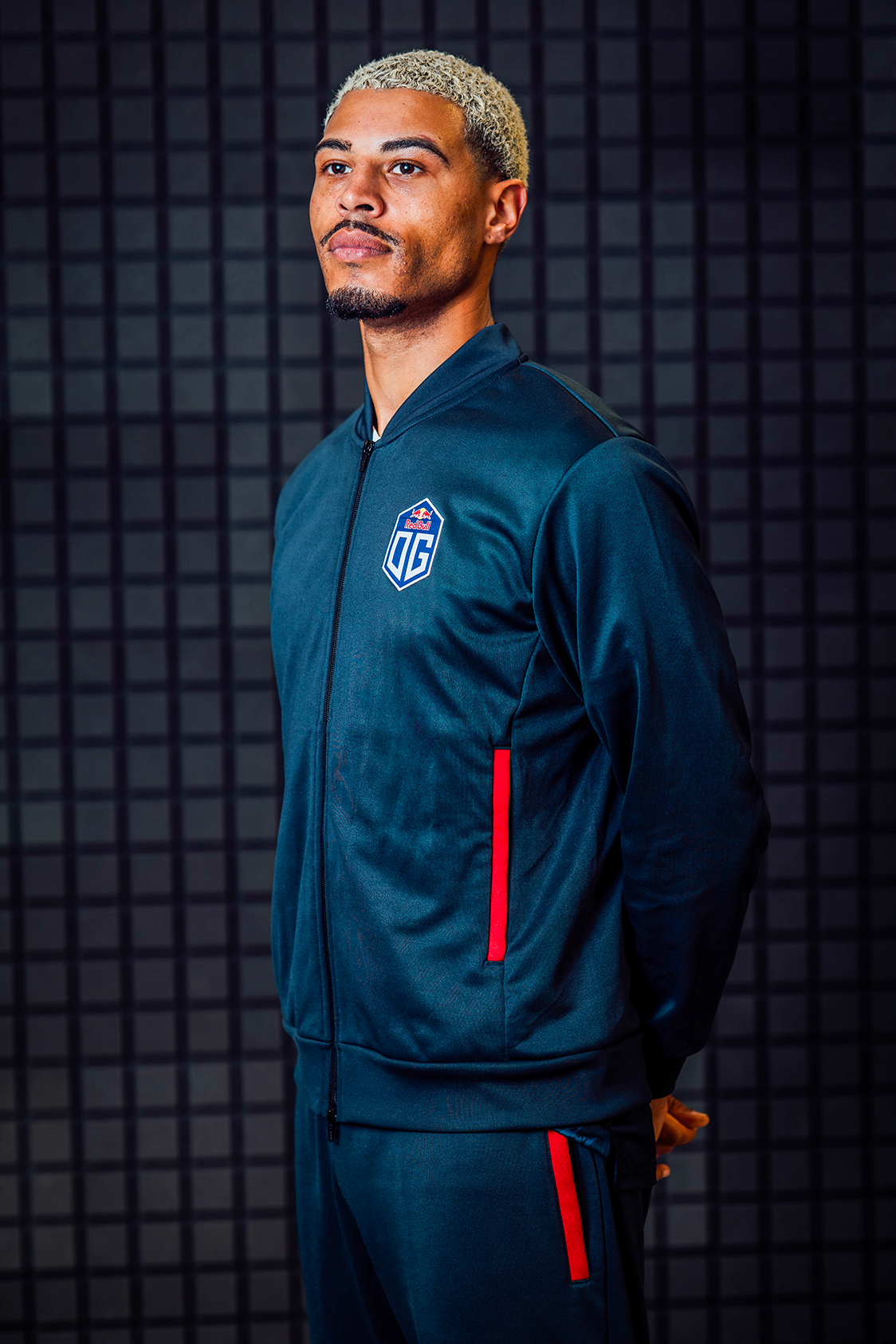 A male model wearing dark blue pro jacket and pants prominently featuring the OG logo.